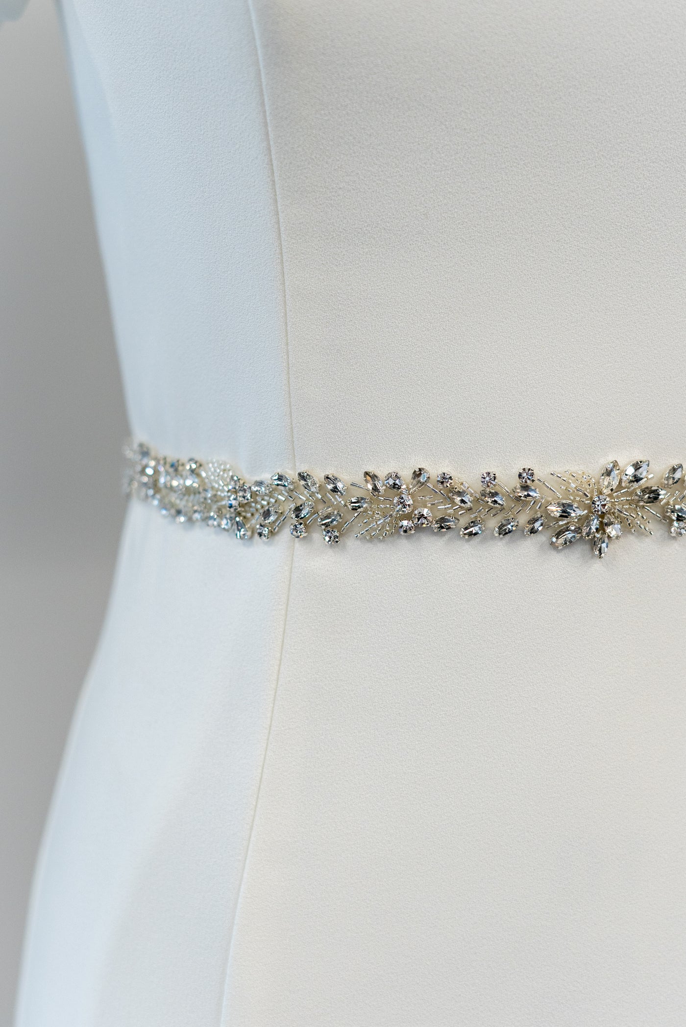 A beautiful beaded belt with a leaf-like design and transparent background to effortlessly dress up a modest wedding dress.