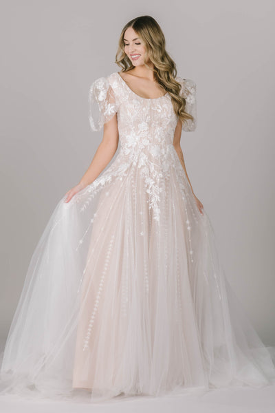 Another picture modest wedding dress in Utah with an a-line silhouette, stunning sheer, lace puff sleeve, and falling lace. It's the perfect garden party dress!