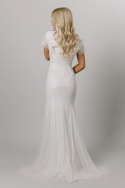 Back view of modest wedding dress with flutter sleeves and v-neckline. It is a fitted dress with sequin beading. This Moments Made Bridal dress is stunning on any body type.