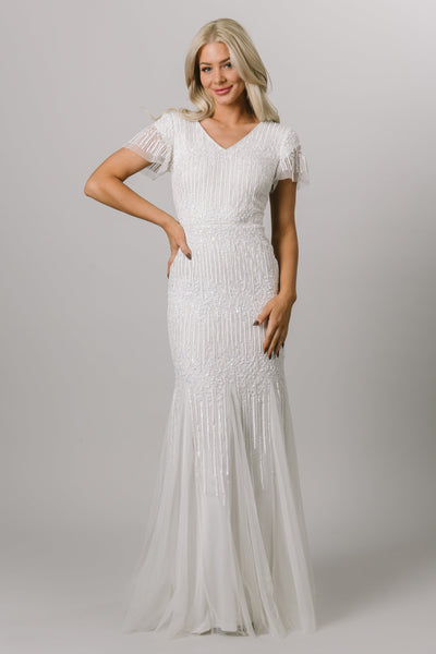 Modest wedding dress with flutter sleeves and v-neckline. It is a fitted dress with sequin beading. This Moments Made Bridal dress is stunning on any body type.