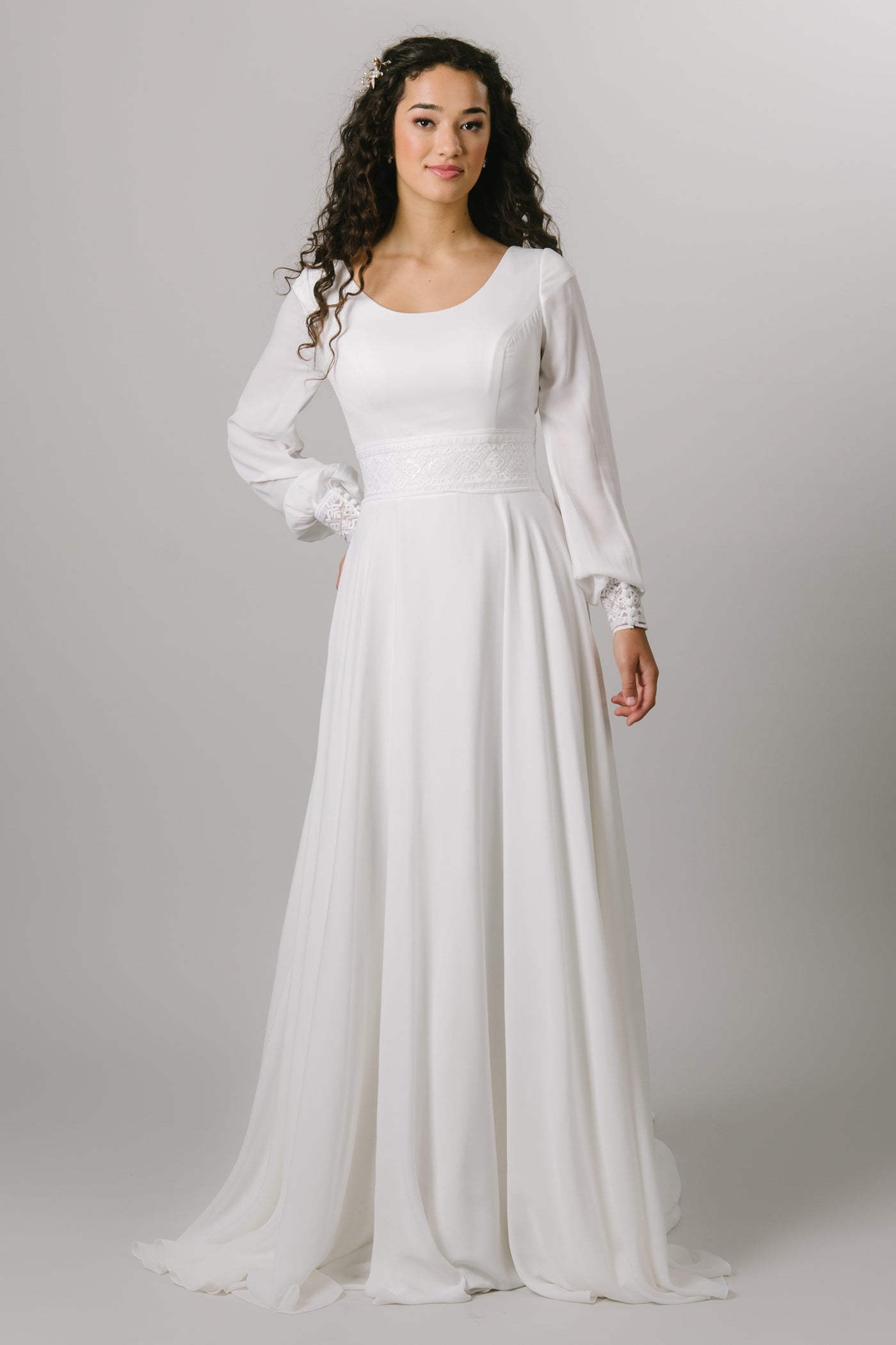 This simple modest wedding gown features long sleeves, and an A-line silhouette. 