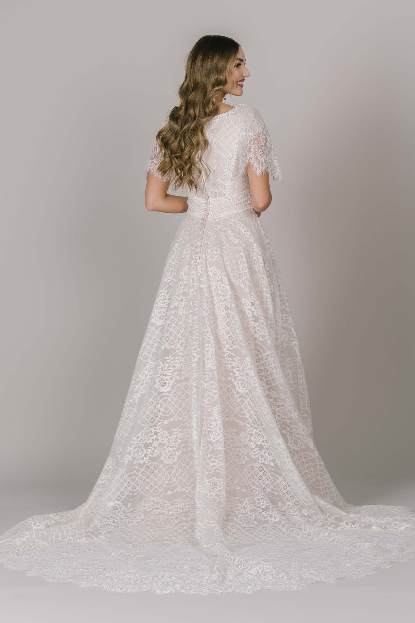 Another back shot of a beautiful modest wedding dress in Utah with a unique and fun lace! The belt comes to a slight angle in the back which perfectly compliments all body types!