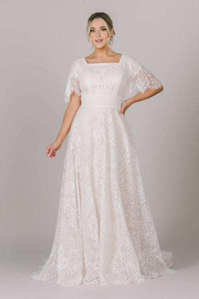 A beautiful modest wedding dress in Utah with a stunning lace, square neck, and flutter sleeves. The lace belt and seams make it perfect for all body types! It's absolutely stunning.
