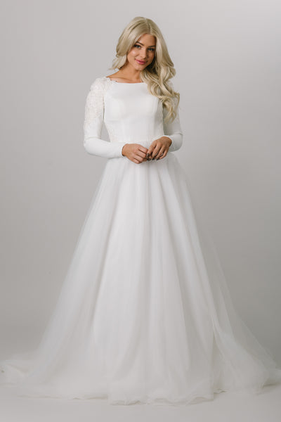 Moments Made Bridal wedding dress with long sleeves. This modest wedding dress has a high scoop neckline and a-lin fit. This is a perfect wedding dress for those cooler months. It has a zipper covered by buttons down the back.