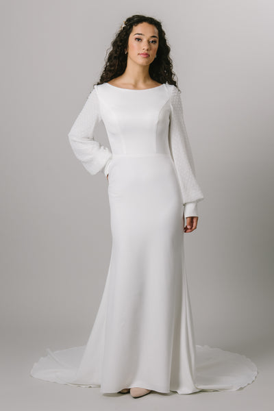 A beautiful modest wedding dress with a simple crepe fabric and pattern. The long bishop sleeves have a beautiful swiss dot pattern.