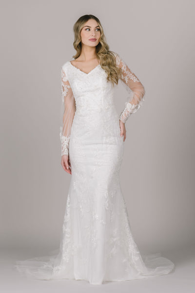 A picture of a fitted modest wedding dress with a beautiful beaded lace detail, v-neckline, and bishop sleeves
