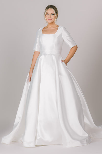 A picture of a simple, modest wedding dress with a stunning square neckline, 3/4 sleeves, and complimentary ballgown silhouette.