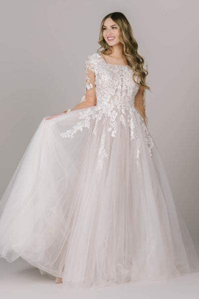The Rayne is a stunning modest wedding dress ong sleeve lace dress with a square neckline and flattering A-line fit. This modest wedding dress exudes elegance and grace.