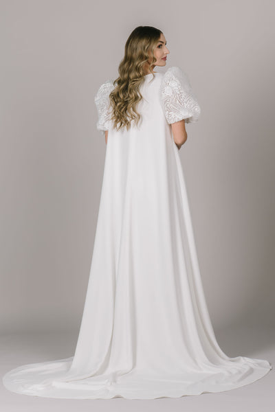 A back shot of the two piece jumpsuit with the matching cape that features lace puff sleeves.