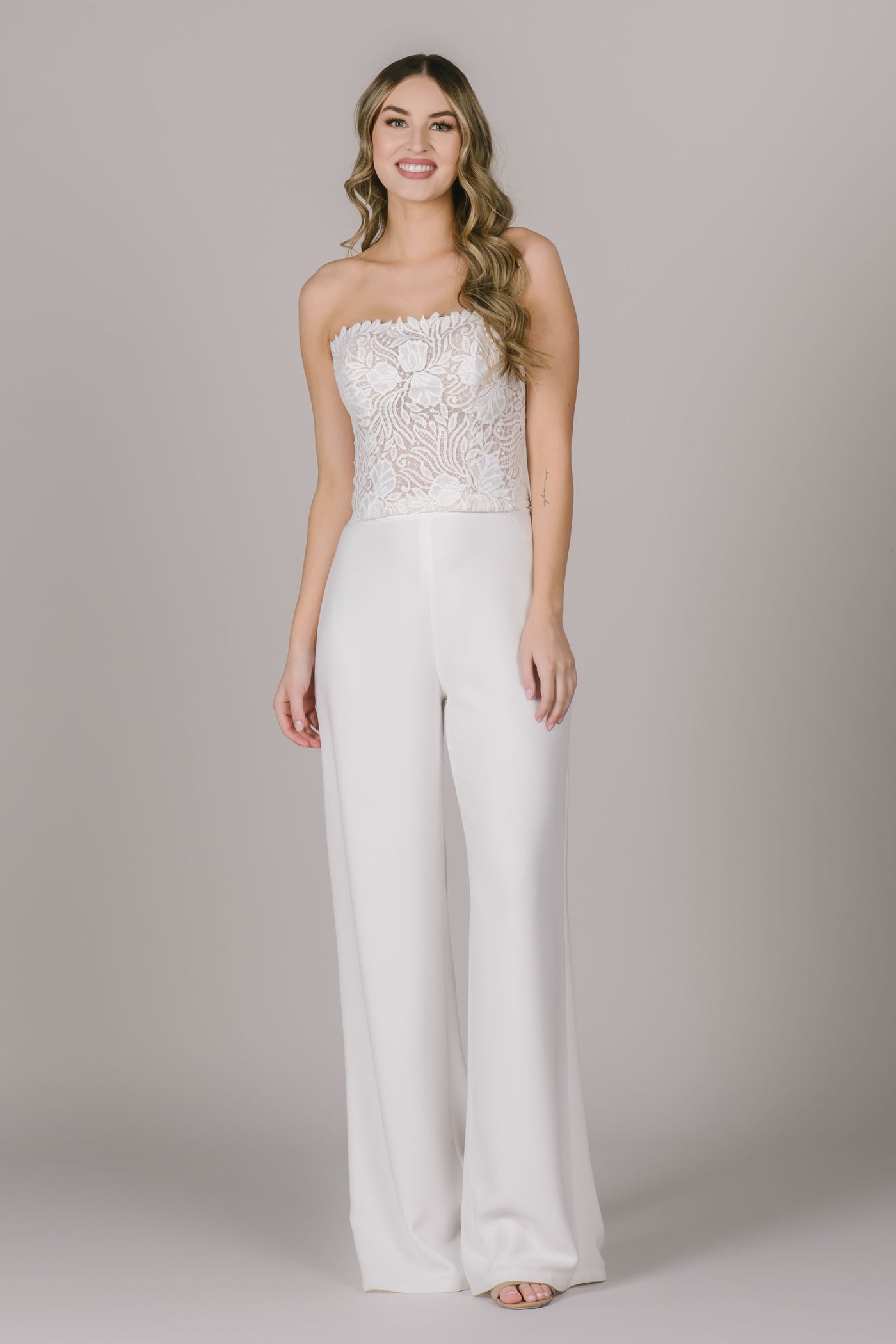 A stunning two piece jumpsuit with a sleeveless lace top and flowy white pants. The underlay on the top is nude which makes the lace stand out so well!