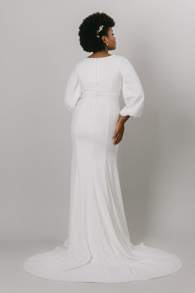 Back shot of a fitted modest wedding dress that includes a simple crepe fabric and bishop sleeves.