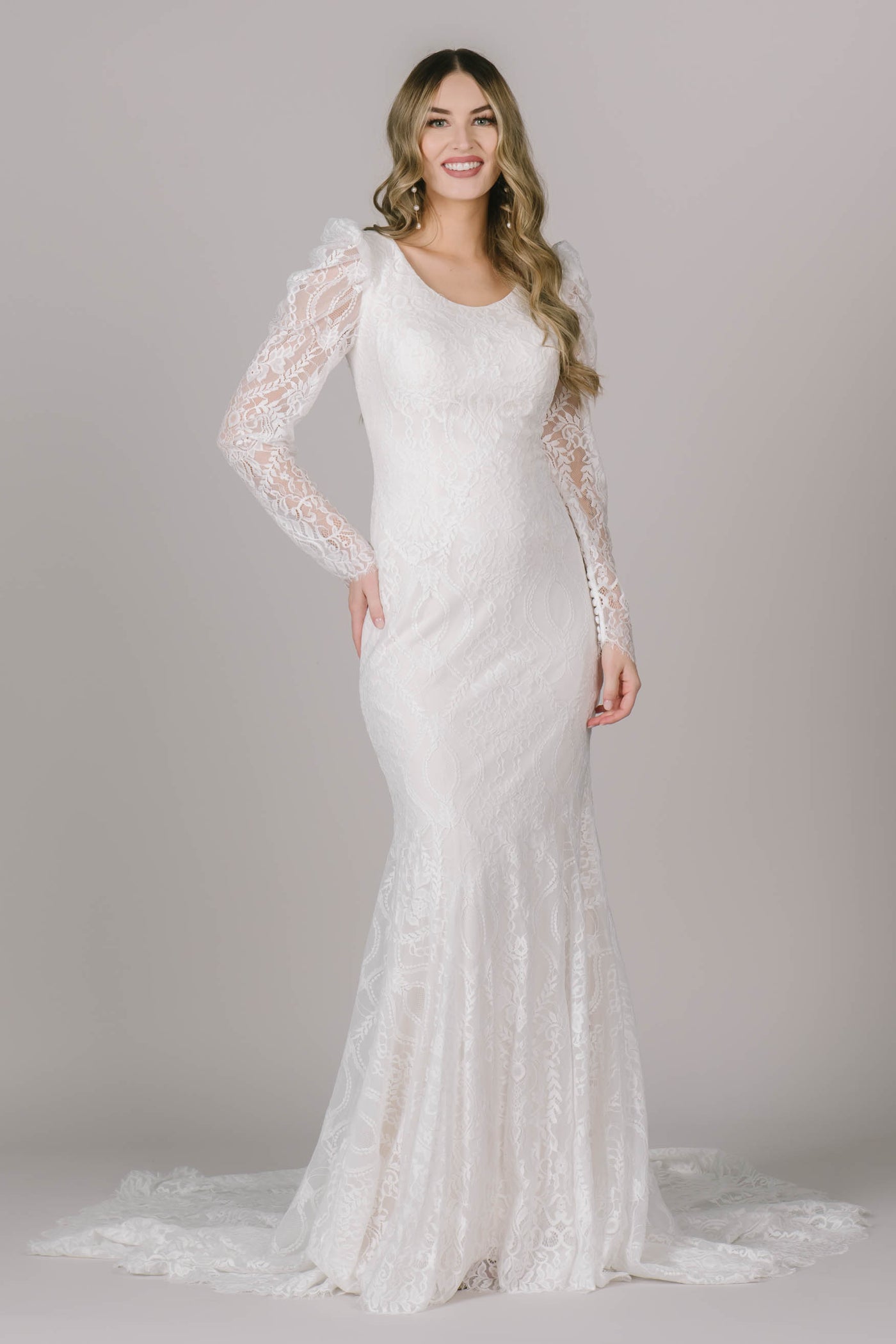 The Vivienne is a fitted modest wedding dress in Utah with a beautiful lace, scoop neck, and long sleeves with a hint of volume at the top. 