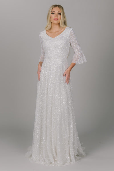 Sparky modest wedding dress with trumpet-like sleeves. It is a-line and has a v-neckline. This dress is covered in sparkly sequins. This modest wedding dress is all about the glam and glitter.