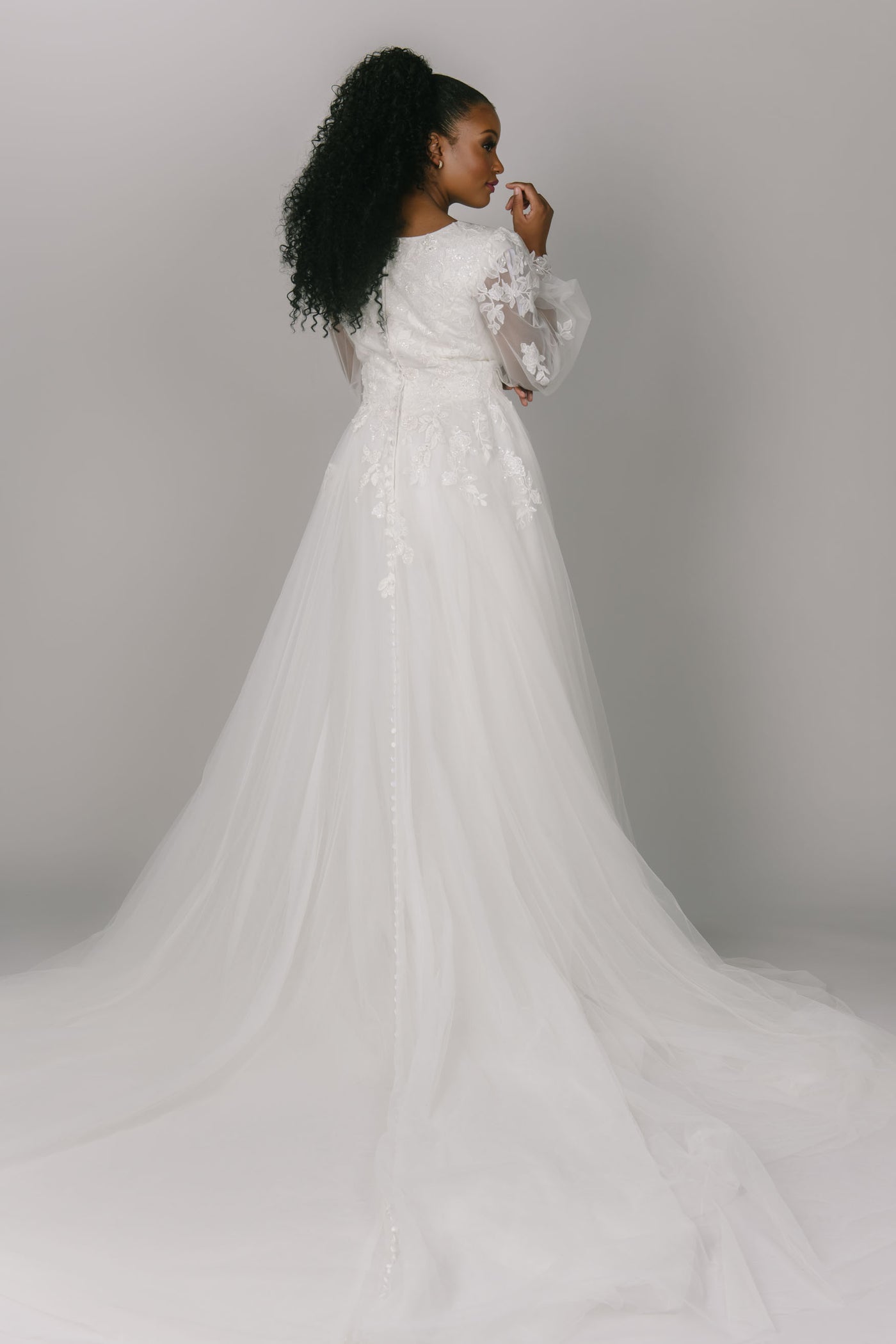 Back view of modest wedding dress, featuring lace bishop sleeves. It has a sweetheart neckline and tulle skirt. It has leaf-like lace that covers the sleeves and top of the dress. The Benny dress is the perfect a-line modest wedding dress.