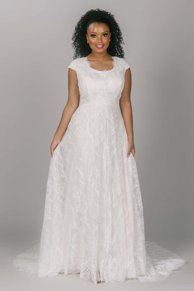 Complete lace modest wedding dress with scoop neckline. This dress is a-line and has cap sleeves. It has a longer lace train and dipped waistline. This dress is perfect for the modest wedding dress woman who wants lace. 