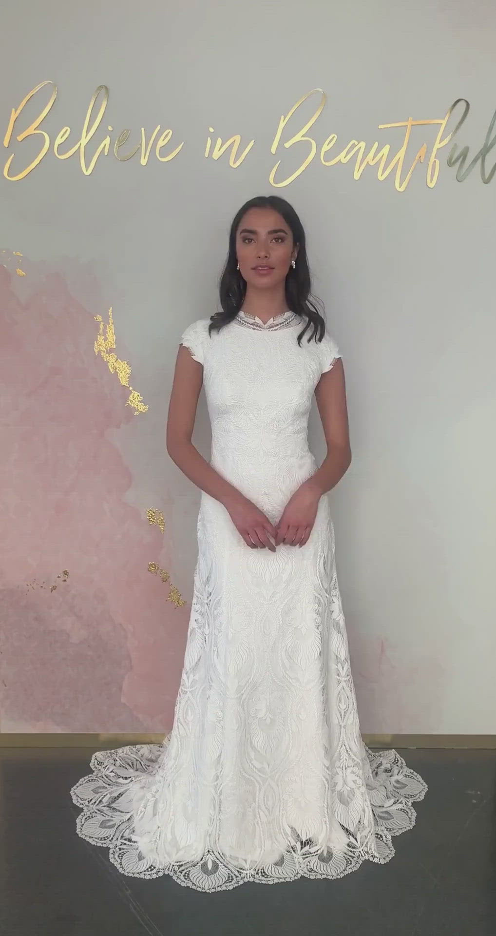 A video featuring our Mary wedding dress and its stunning, unique lace pattern, chic high neckline, and sheath fit.