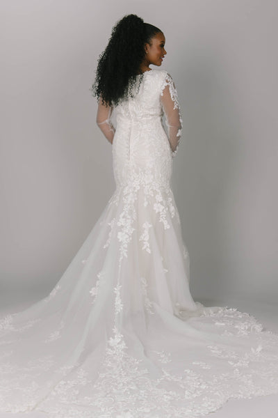 Back view of fitted modest wedding dress. This dress has flower/vine lace which creates a gorgeous lace train. It has long sleeves and a v-neckline.