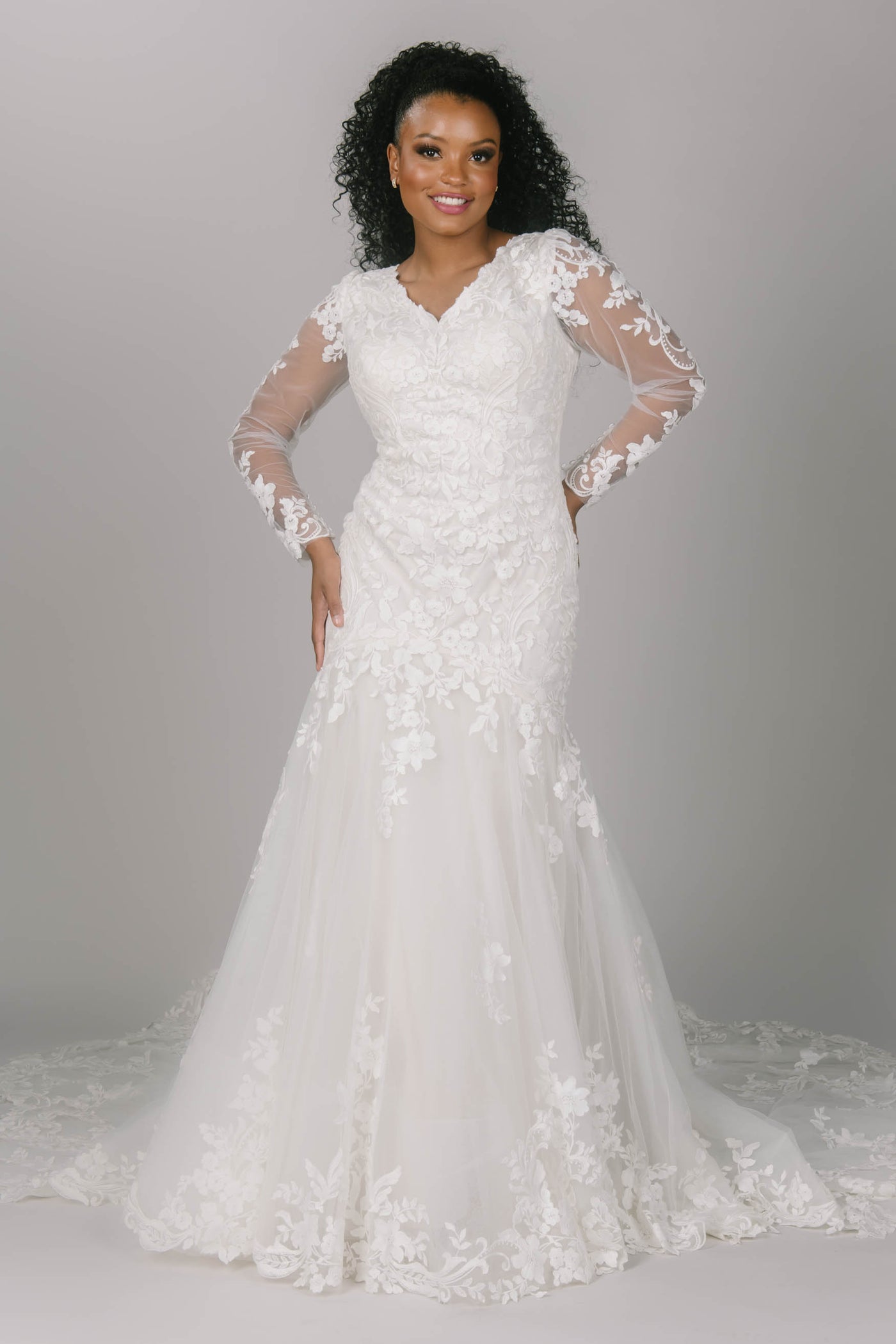 Front view of fitted modest wedding dress. This dress has flower/vine lace which creates a gorgeous lace train. It has long sleeves and a v-neckline. 