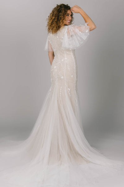 Back view of modest wedding dress with flutter sleeves. It has beading and lace. The tulle skirt and sleeves give it flow and movement. It is a gorgeous modest wedding dress. 