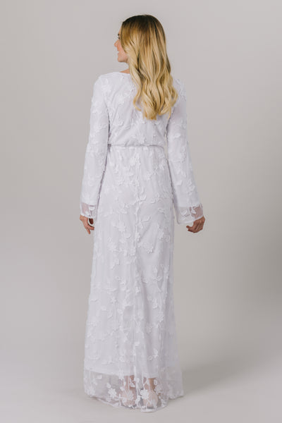 This LDS temple dress features a fully lined, floral lace with a cinched waistband and flowy long sleeves. It includes two pockets. This temple dress is from LatterDayBride in downtown Salt Lake City.