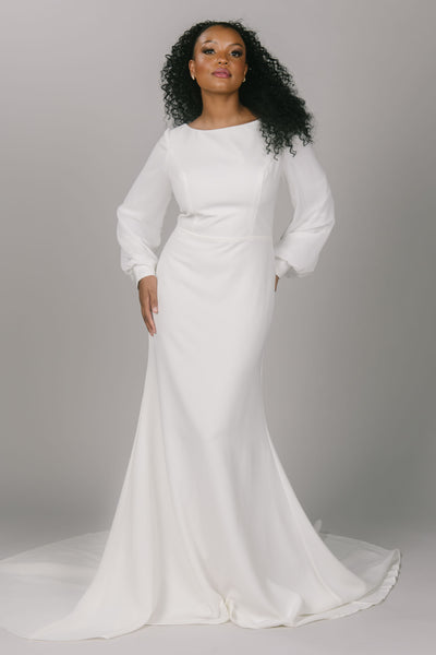 Front view of simple modest wedding dress with bishop sleeves. It has an a-line skirt and buttons all the way down. It has a scoop neckline. Stunning simple modest wedding dress.