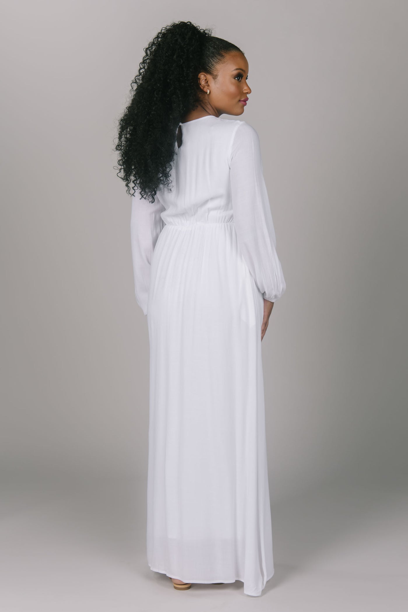 Back view of temple dress with a little bit of lace. It has vertical strips of lace on the top of the dress. It has a simple skirt and bishop styled sleeves. The high scoop neckline and pockets of this dress make it very efficient.