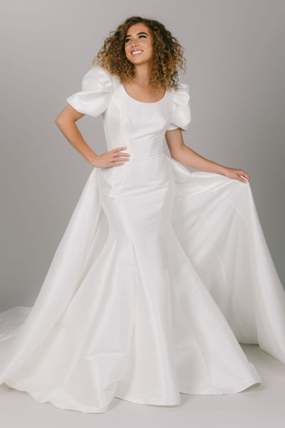 View with overskirt of modest wedding dress with contour lines. It is a fitted dress with puffed sleeves. This dress has a scoop neckline and is a gorgeous modest wedding gown.