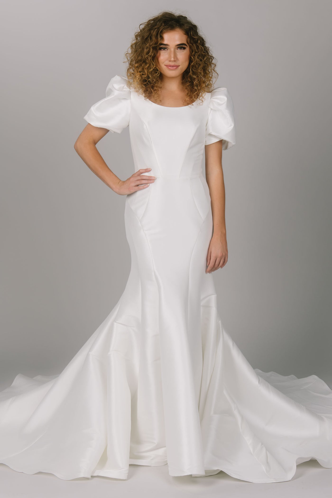 Front view of modest wedding dress with contour lines. It is a fitted dress with puffed sleeves. This dress has a scoop neckline and is a gorgeous modest wedding gown. 