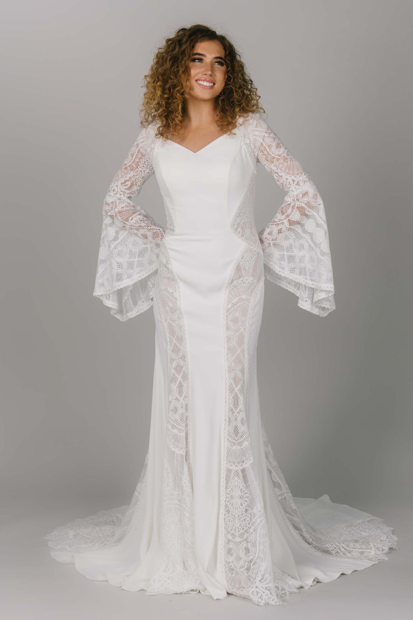 Front view of modest wedding dress with bell sleeves. This boho styled dress has dedicate sheet lace and a v-neckline. It is a fitted dress and perfect for that modest bride. 