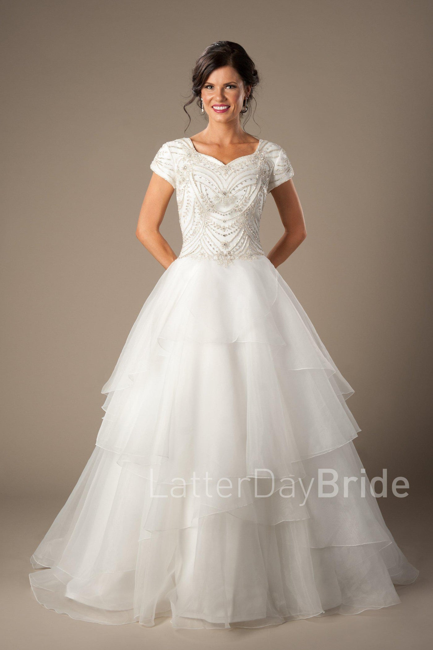 Elaborate beadwork and flowing tiered modest wedding dress, style Weismann, is part of the Wedding Collection of LatterDayBride, a Utah Wedding Shop. 