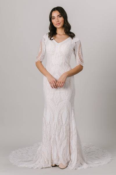 This fitted modest wedding dress has a lovely v-neck and a unique lace pattern that creates the most darling illusion half sleeves. 