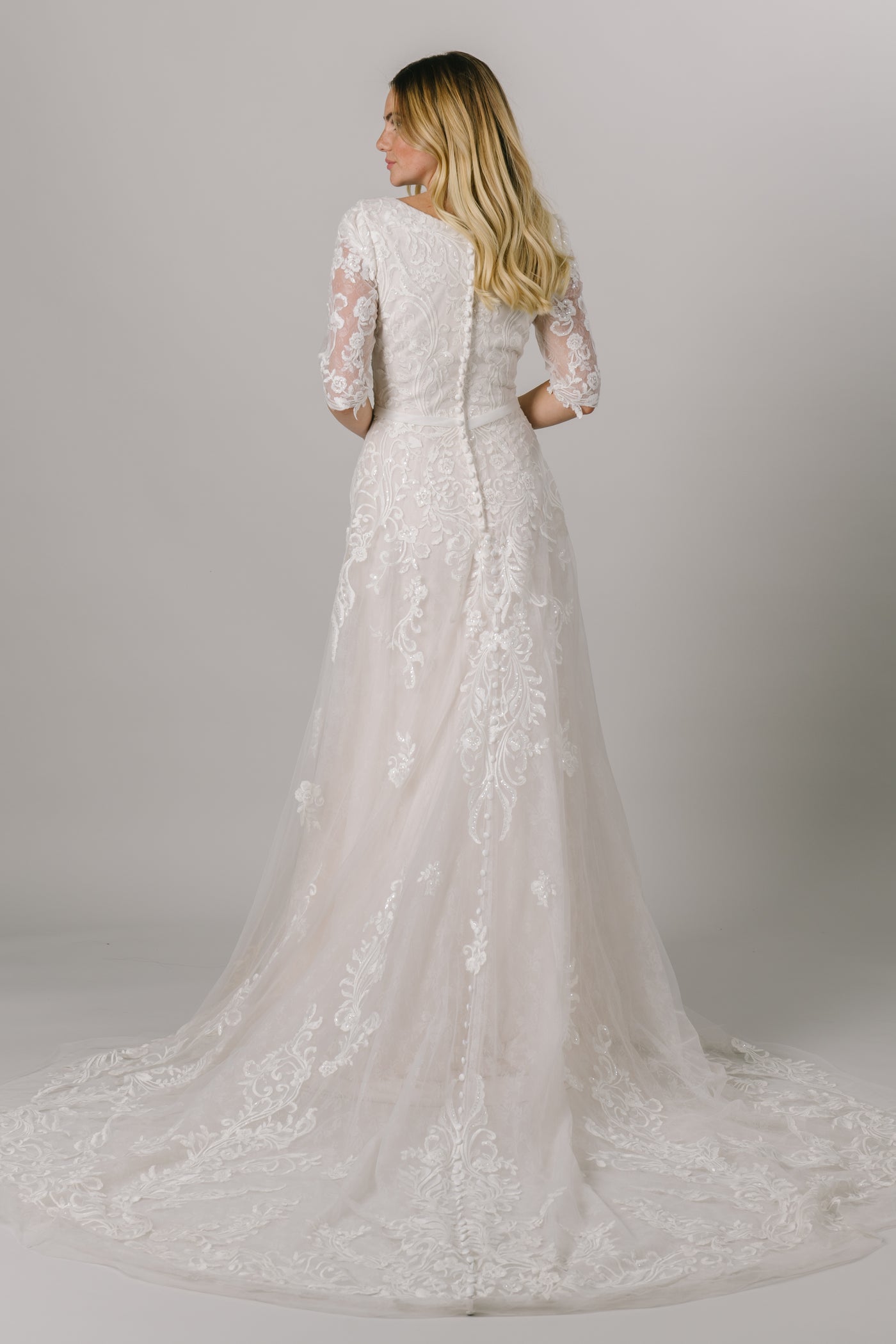 This modest wedding dress has a flattering a-line fit with an absolutely gorgeous lace pattern. With half sleeves and buttons down the back, how could we say no?  Style Love: Little belt with an adorable bow to accentuate the waist! From a bridal shop in downtown Salt Lake City called LatterDayBride.