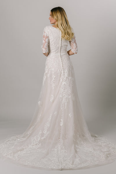 This modest wedding dress has a flattering a-line fit with an absolutely gorgeous lace pattern. With half sleeves and buttons down the back, how could we say no?  Style Love: Little belt with an adorable bow to accentuate the waist! From a bridal shop in downtown Salt Lake City called LatterDayBride.