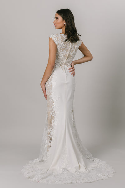This fit-and-flare, modest wedding dress features gorgeous lace detailing at the top and own the sides of the dress. There are buttons down the back that add a darling compliment to the lace. Shown in Ivory/Nude/Ivory.  Style Love: Nude lining helps the lace pop! From LatterDayBride is Salt Lake City, Utah.