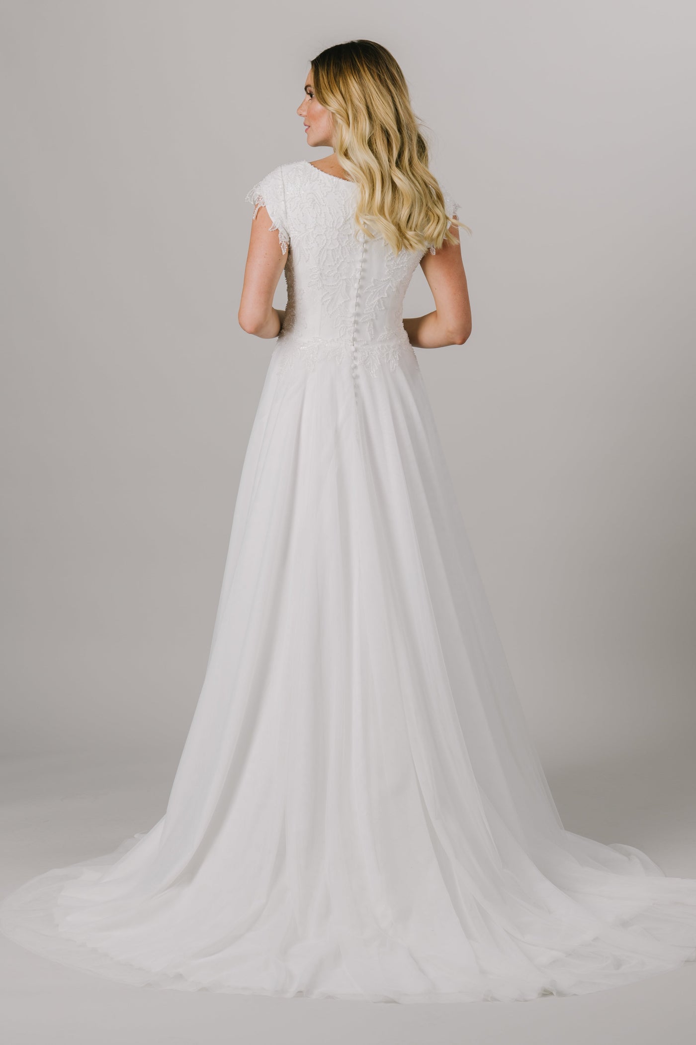 This a-line modest wedding dress features the most unique beading throughout the bodice. This lightweight and flowy gown features a boat neckline and gorgeous short sleeves.   ﻿Style Love: This dress is part of our brand new, exclusive LatterDayBride wedding dress collection. The back view of the dress from a bridal store in SLC, Utah. 