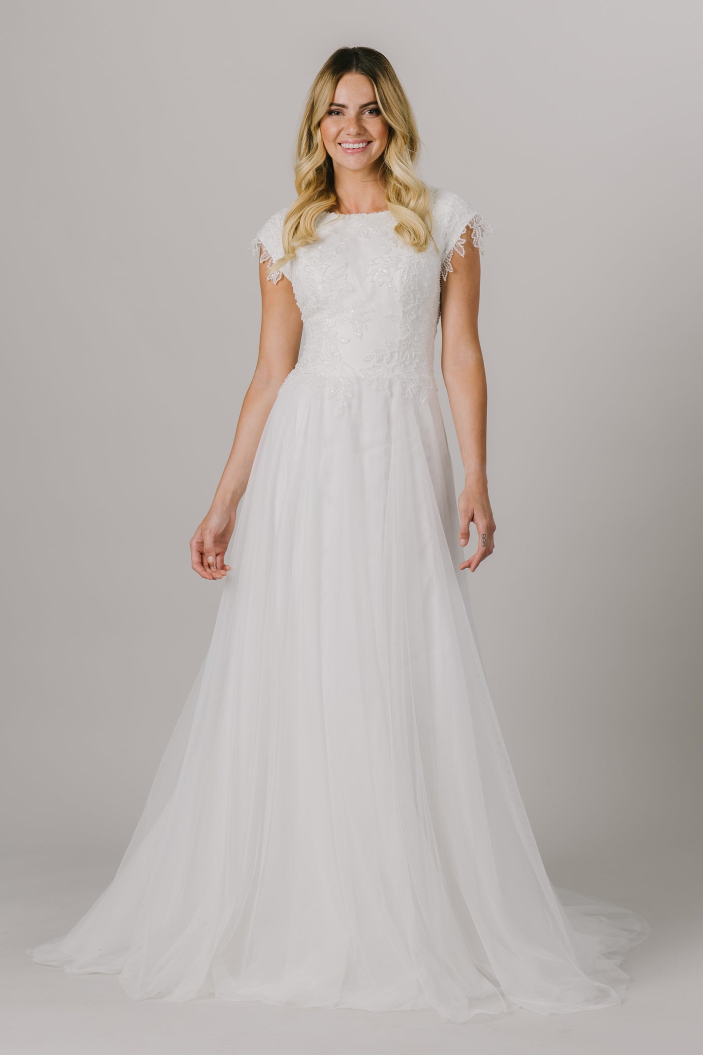 This a-line modest wedding dress features the most unique beading throughout the bodice. This lightweight and flowy gown features a boat neckline and gorgeous short sleeves.   ﻿Style Love: This dress is part of our brand new, exclusive LatterDayBride wedding dress collection.