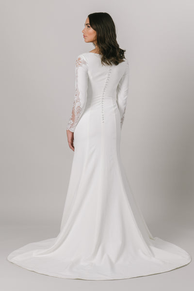 For all of our vivacious and fun brides, this modest wedding dress is for you. This fitted gown features long sleeves and a v-neckline. The otherwise simple dress has a gorgeous lace detail down the sides of the sleeves.  ﻿Style Love: This dress is part of our brand new, exclusive LatterDayBride wedding dress collection.