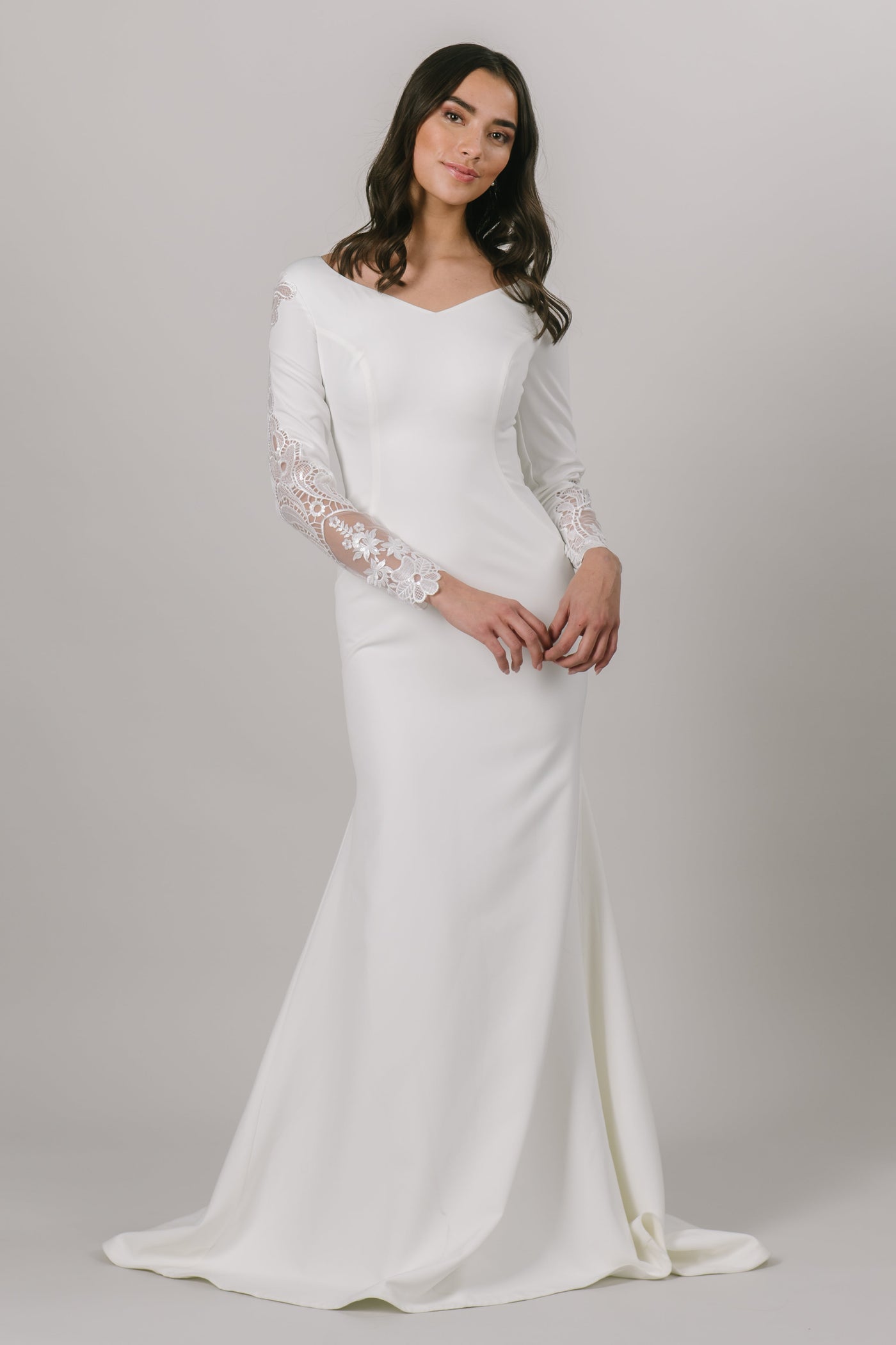 For all of our vivacious and fun brides, this modest wedding dress is for you. This fitted gown features long sleeves and a v-neckline. The otherwise simple dress has a gorgeous lace detail down the sides of the sleeves. 