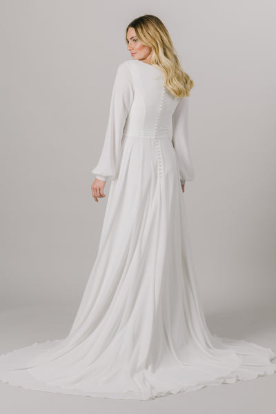A long sleeve dream, this modest wedding dress is the perfect mixture of style and sophistication. This dress features a small belt around the waistline, a scoop neckline and bishop sleeves.  ﻿Style Love: This dress is part of our brand new, exclusive LatterDayBride wedding dress collection. The Back of the dress from a bridal store in downtown, SLC, Utah. 