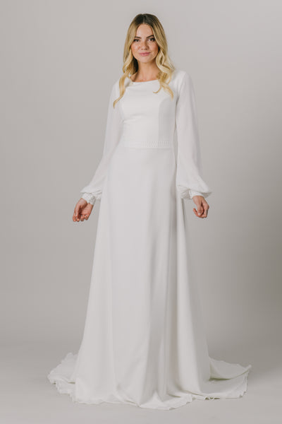 A long sleeve dream, this modest wedding dress is the perfect mixture of style and sophistication. This dress features a small belt around the waistline, a scoop neckline and bishop sleeves.  ﻿Style Love: This dress is part of our brand new, exclusive LatterDayBride wedding dress collection.