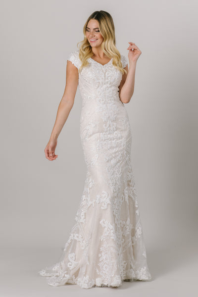 This fit-and-flare, modest wedding dress features a flattering V-neckline and a double lace design that creates amazing dimension.  Available in Ivory/Ivory.