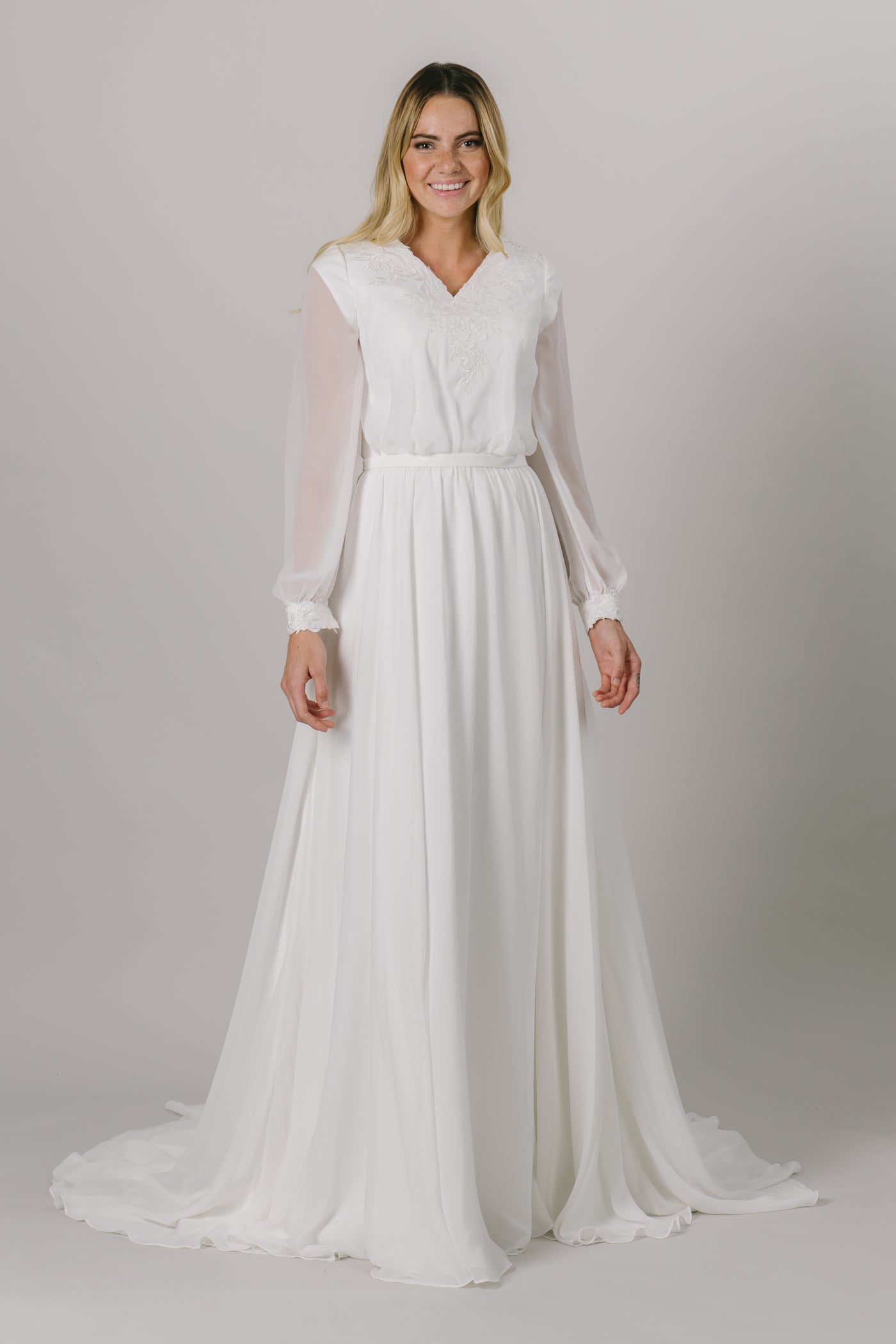 This long-sleeve modest wedding dress features a v-neckline, bishop sleeves, and an a-line fit that flatters every figure.   Style Love: Gorgeous shimmering lace around the neckline and sleeve cuffs!