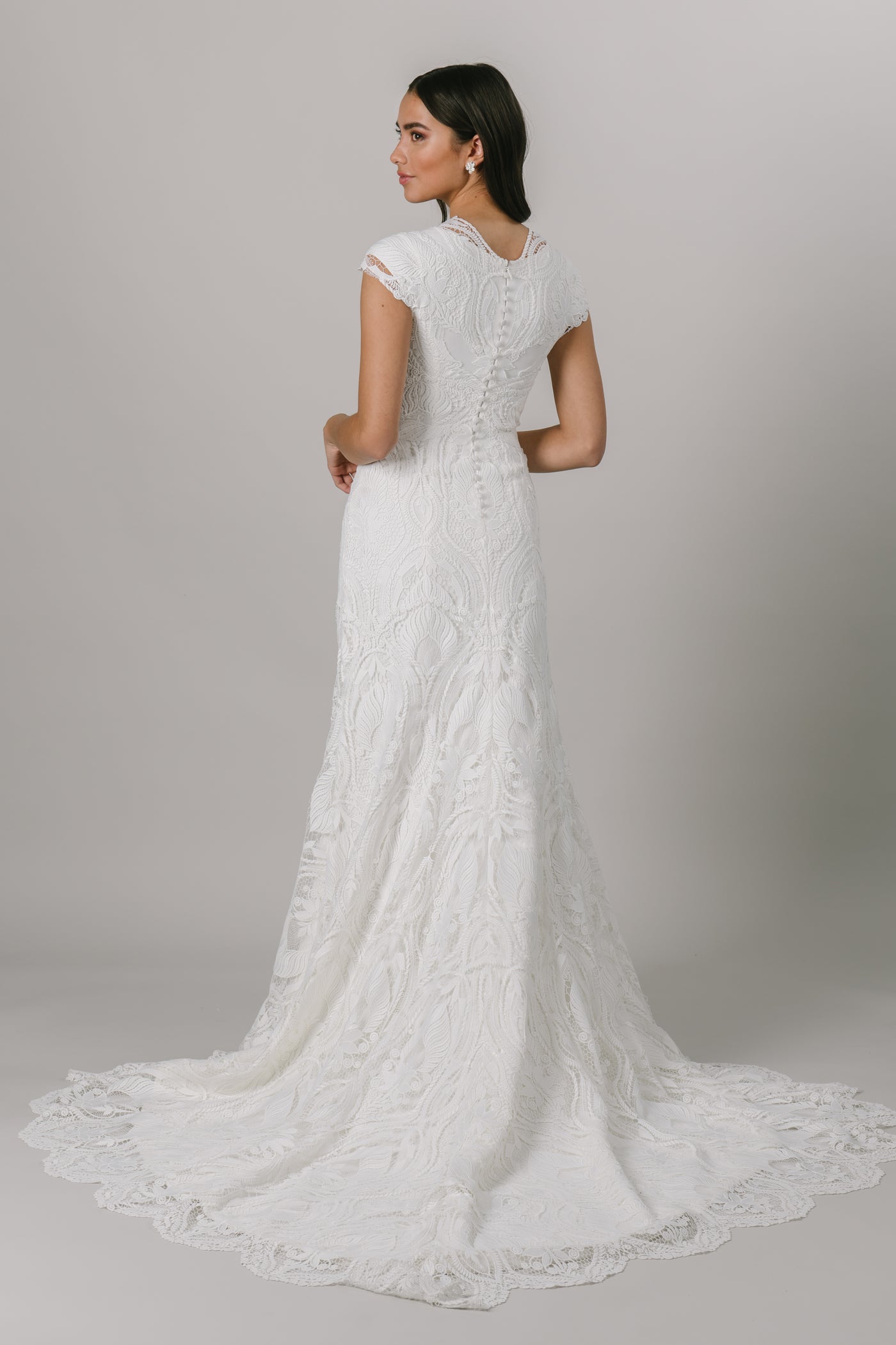 This brand new, modest wedding dress features a flattering fit-and-fall silhouette, a thick lace pattern and an adorable illusion neckline. Available in Ivory/Ivory and Ivory/Cappuccino.  Pictured in Ivory/Ivory. From LatterDayBride in downtown Salt Lake City.