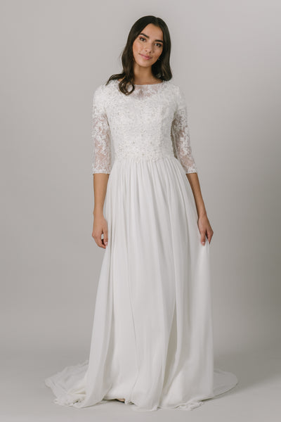 This modest wedding dress has a vintage chic vibe to it and we love it! It features a dazzling dress features lace illusion almost long sleeves, a high illusion neckline, and a flowy chiffon skirt.   Style Love: This gown is the perfect blend between simple and sparkly!