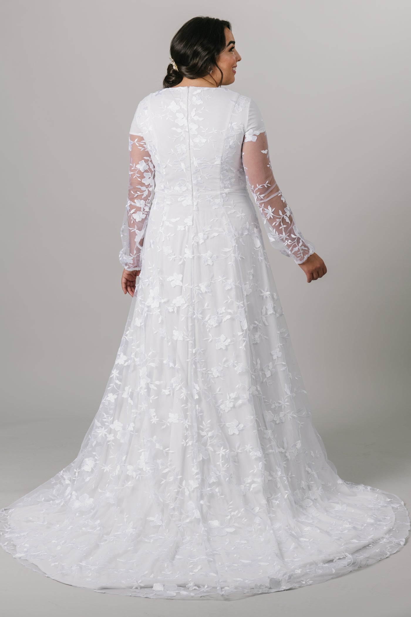 This long-sleeve modest wedding dress features a hand-embroidered lace pattern with an A-line skirt and a prairie chic feel. Plus size available in store.  Style Love: The soft puff of the sleeve is undeniably darling, and we are smitten with the flow of the skirt. Totally twirlable! From a bridal shop in downtown SLC,Utah.