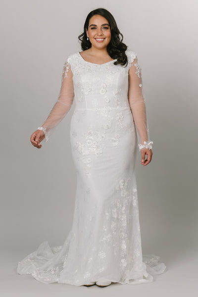 This plus size model is wearing a white modest wedding dress. She is wearing a size 16.