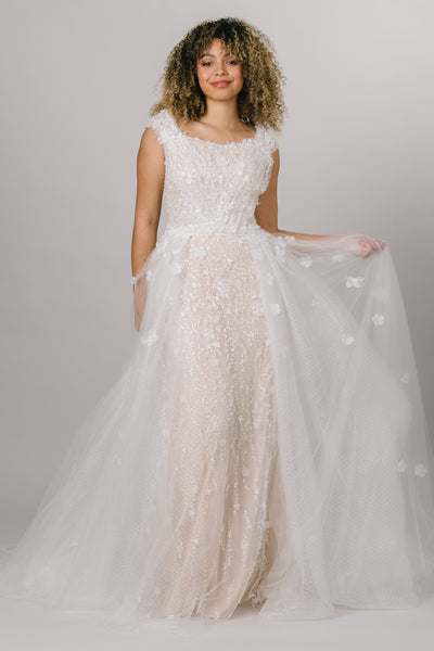 This gown did not miss a detail, featuring sequin detailing, floral and star appliques, and tulle rouching over the bodice. and a tulle overskirt is placed on top.