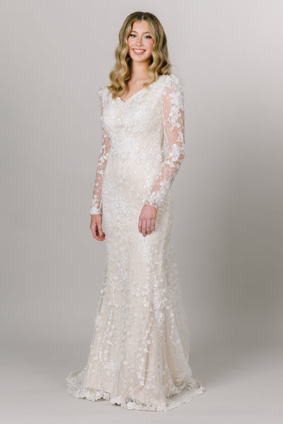 Alternate view of beautiful lace modest wedding dress by Moments Made Bridal. It has a v-neckline with a long lace sleeves. The sleeves have a slight puff at the top of the sleeve. It is a fitted fit with a long gorgeous train.