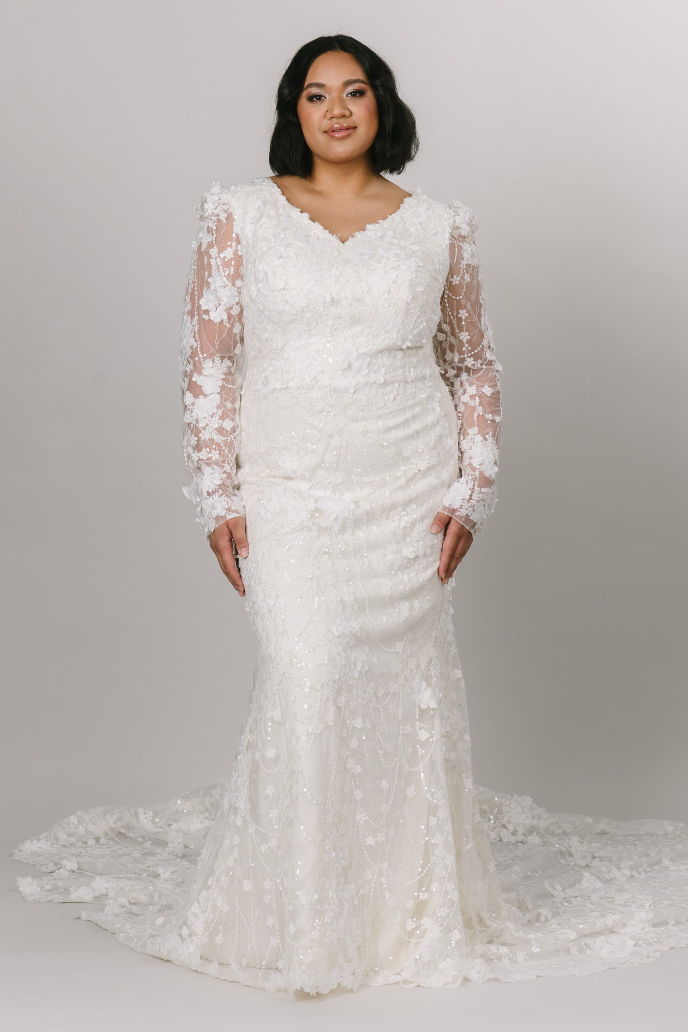 Beautiful lace modest wedding dress by Moments Made Bridal. It has a v-neckline with a long lace sleeves. The sleeves have a slight puff at the top of the sleeve. It is a fitted fit with a long gorgeous train. 