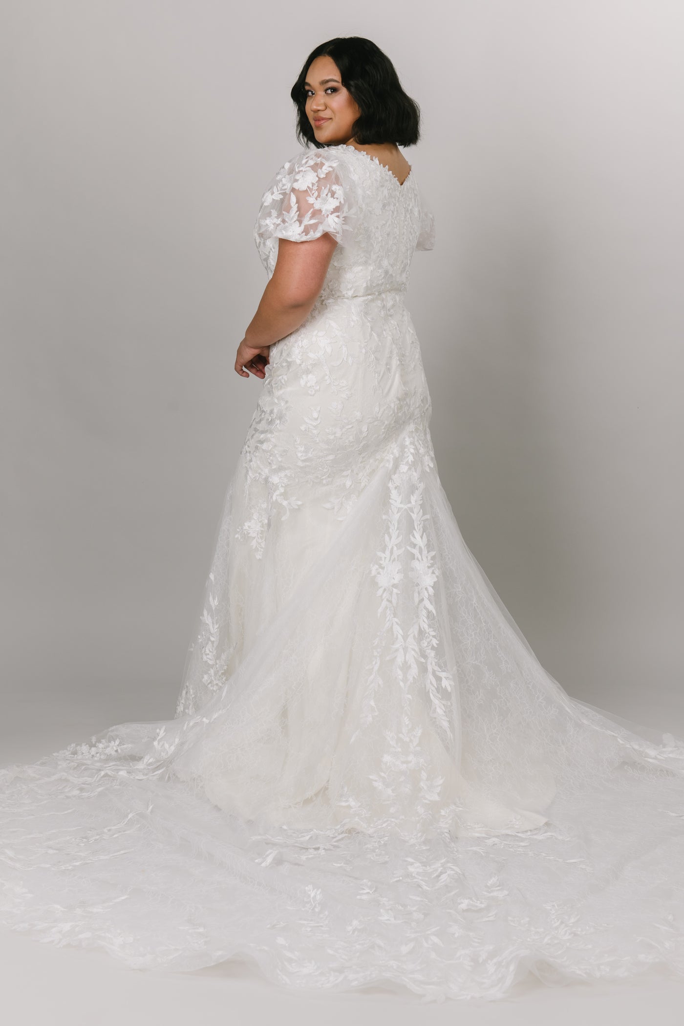Back view of Moments Made Bridal gown with flutter sleeves and v-neckline. It is a fitted dress with a gorgeous long train. It is the perfect modest wedding dress for any season.